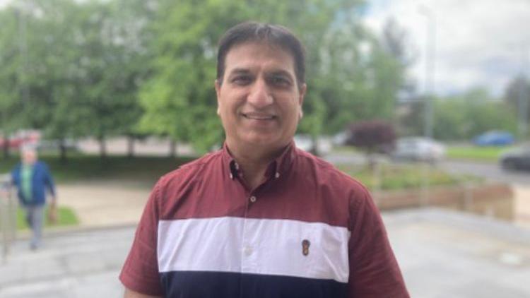 Dr Mukesh Chugh. He has dark hair, wearing a red, white and navy shirt.