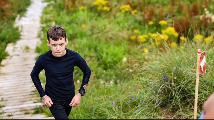 James running through a field with a wooden footpath