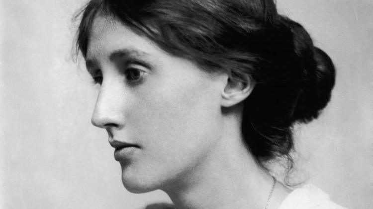 Black and white portrait of a young Virginia Woolf. She is looking to the left with her dark hair up and wearing a white tunic-style top. 