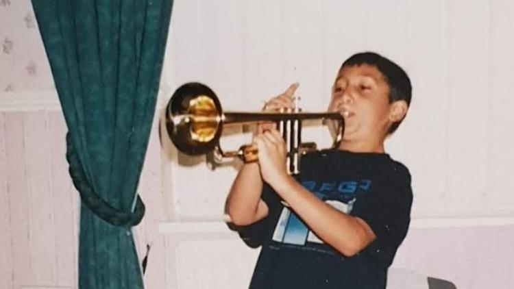 Nadeem, a young boy, blows on a trumpet.