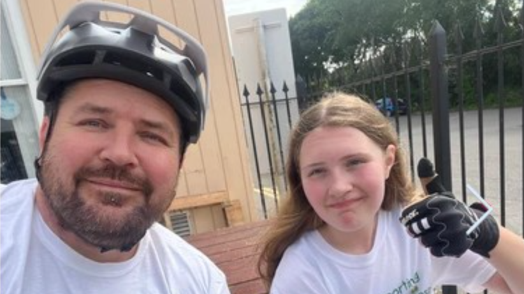 Dad Ian Nash and his daughter Charlie on their bike ride challenge. Mr Nash is wearing a bike helmet.