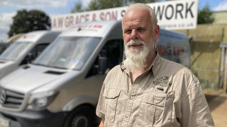 Colin Grace standing in front of vans and AW Grace sign 