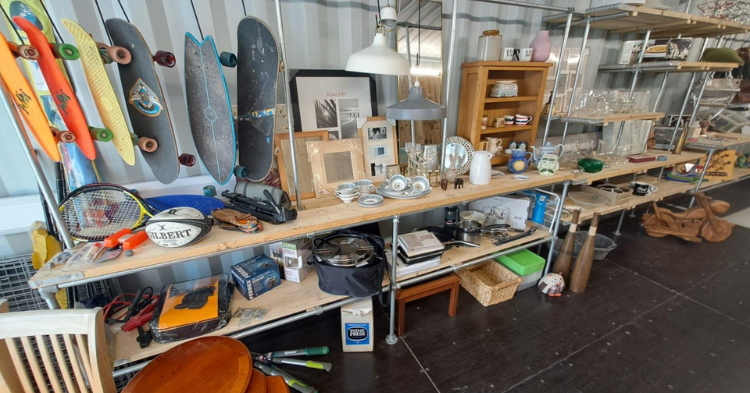 Skateboards, sports equipment displayed in a shipping container in Truro. The items are displayed on shelving which is scaffold boards held up by scaffolding.