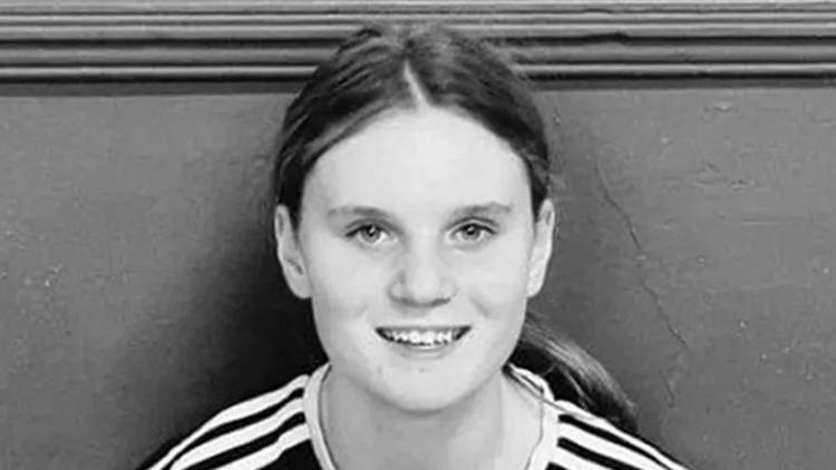 A black and white photo of a young girl with her dark hair in a ponytail smiling at the camera.