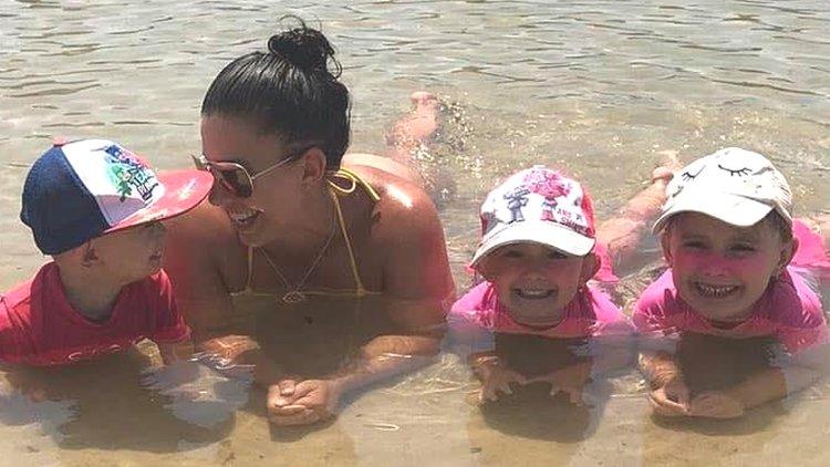 Hannah Baxter and her three children lie on a beach