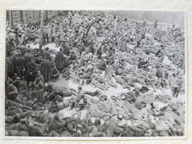 Hundreds of people crowd a courtyard - some curled on the ground, apparently asleep, with others sitting or standing in small groups.