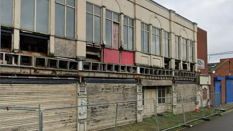 The exterior of a derelict former nightclub showing shutters and barricades around it