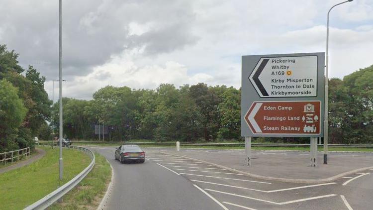 The junction of the A169 and A64. There is a road sign directing drivers to Pickering and Whitby on the right hand side of the road.