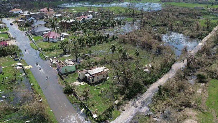 An area photo showing tropical roads flooded and roofs off houses ripped off.
