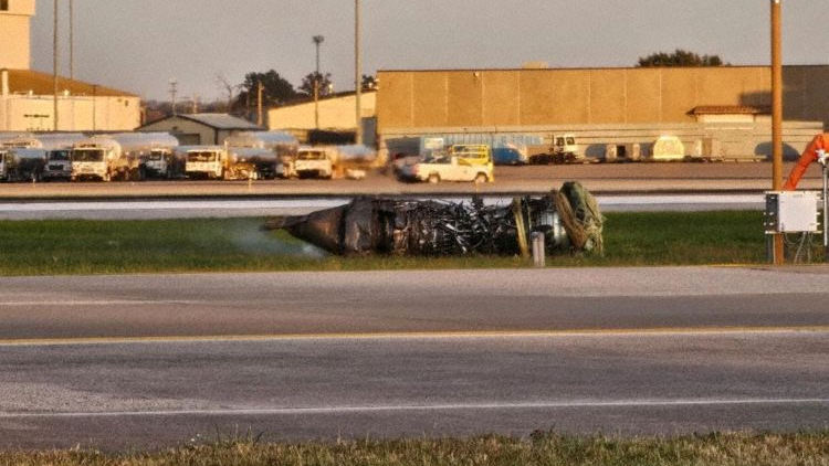 The smoking remains of an engine sitting on the grass next to the runway at Louisville International Airport.