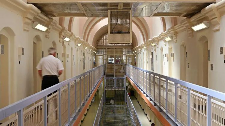 A prison guard walks around a corridor in a prison