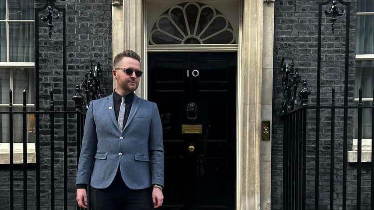 James Clarke, wearing a jacket and dark glasses, stood outside the door of 10 Downing Street