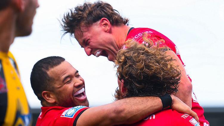 Salford Red Devils player Joe Mellor shouts in celebration and is embraced by teammates after scoring a try against Castleford Tigers.