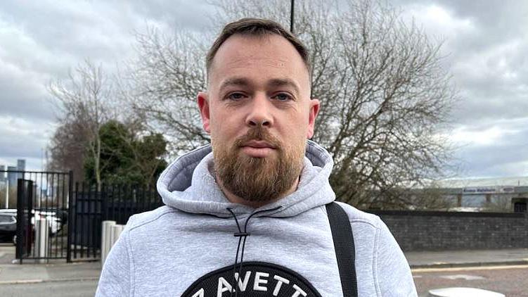 Manchester United fan Ian with brown hair and beard wearing a grey hoodie.