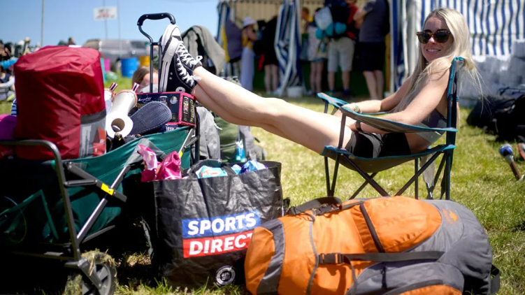 Girl waits in the sun with all her bags 