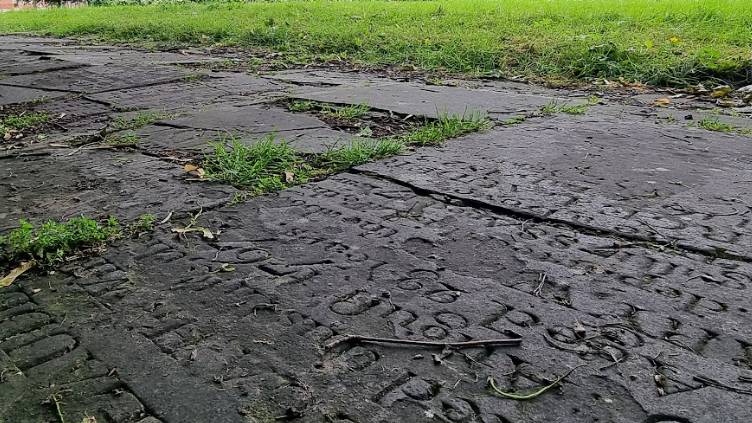 A series of several flat and inscribed grave stones in green space