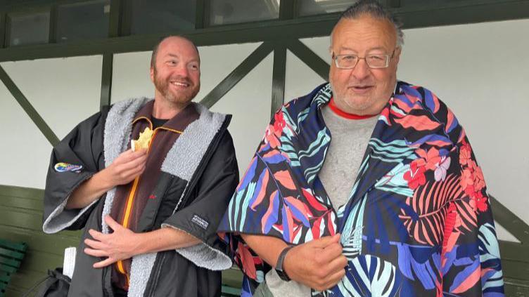 William Beebe and Graham Spencer standing in the lido pavilion after their swim, dressed in a towel and a dry robe