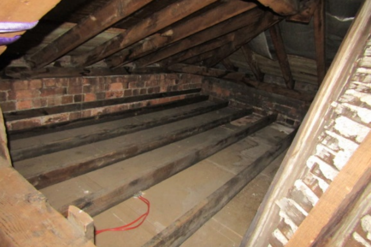 A photo of the loft space above the Market Hall shows beams and joists, some of which are reported to have been water-damaged.