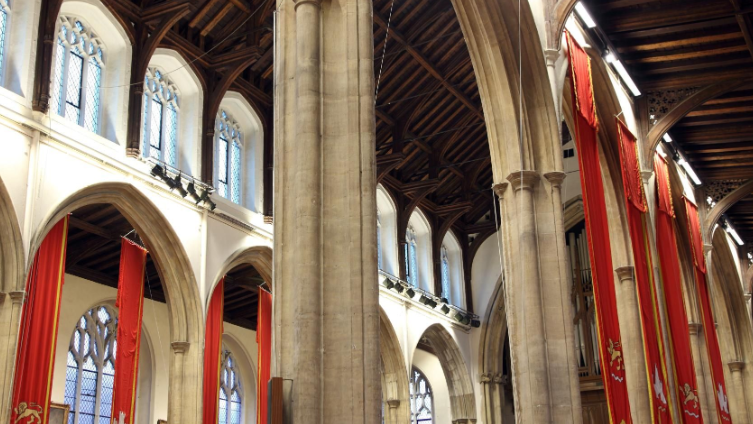 The interior of St Andrews Hall. We can see several tall columns and red banners hanging from the ceiling