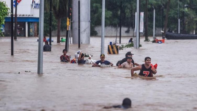 People cross an avenue flooded by the passage of Hurricane John in the upper part of the port of Acapulco, in Guerrero, Mexico, 27 September 2024