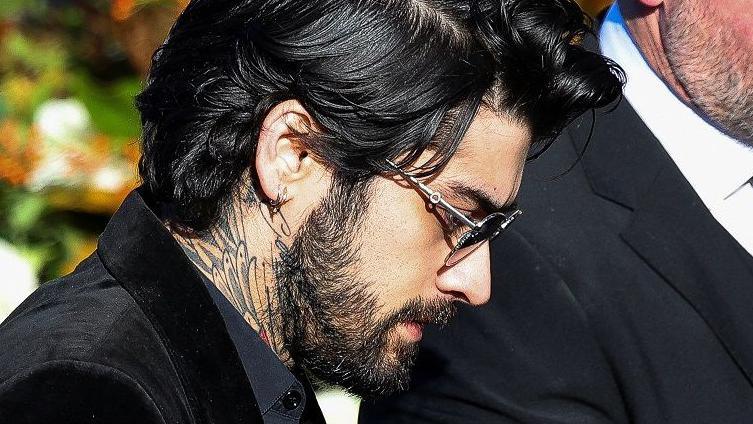 Zayn Malik at the funeral, also seen wearing a smart dark jacket and sunglasses