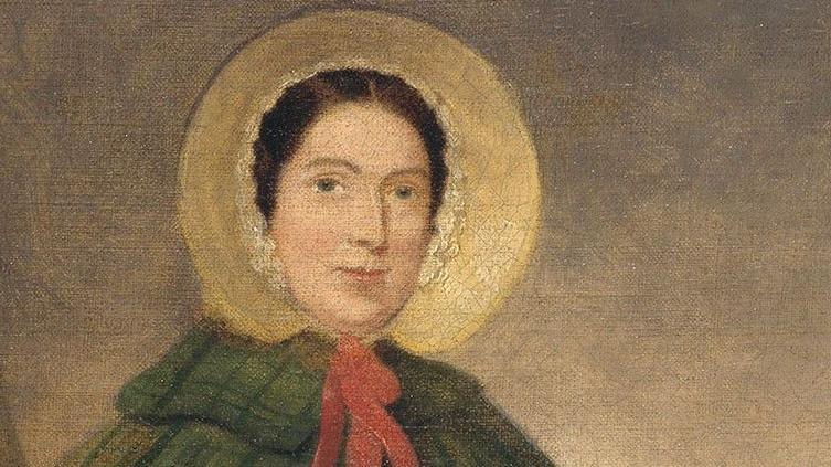 Head and shoulders detail of a painting depicting Mary Anning from the early 1800s. She has dark eyes and dark hair parted in the centre and is wearing a straw-coloured bonnet with a brim, tied with a red ribbon, and a dark green tartan cloak with a collar.