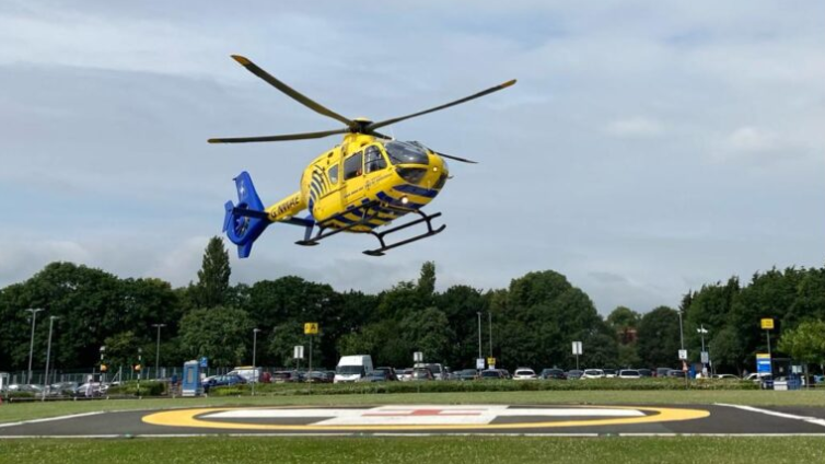 A yellow helicopter about to land at the hospital helipad