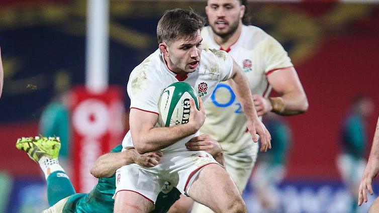England A players celebrating a try during their dominant match against Ireland XV at Thomond Park, with fans in the background.