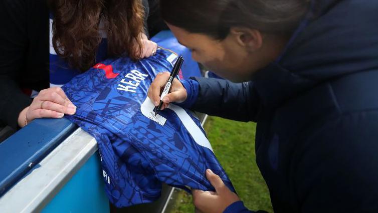 Sam Kerr signing a shirt