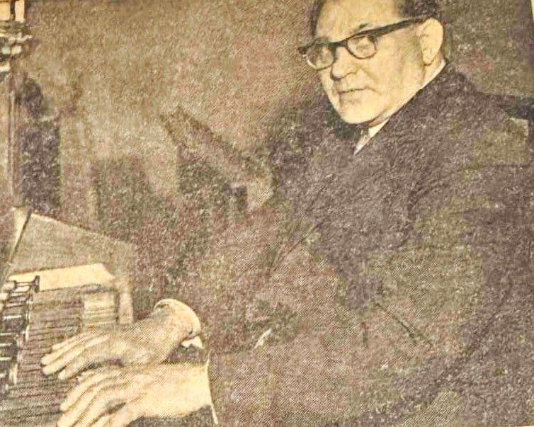 Walter Hambock looking at the camera in a black and white photo, sitting at an organ.