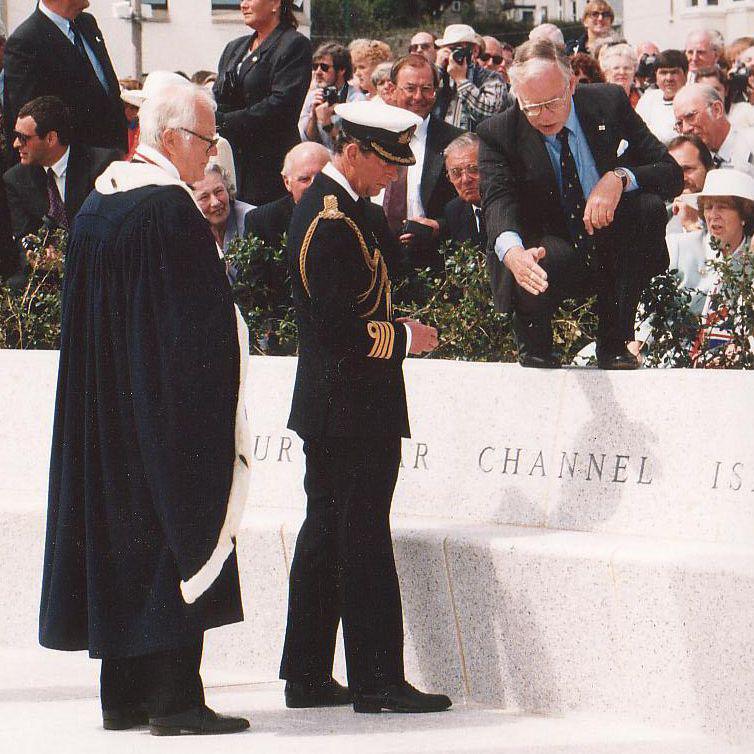 Two men looked on as another man points to the sundial