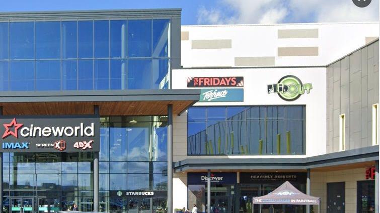 Part of Rushden Lakes shopping centre, showing the glass and steel entrance to Cineworld on the left, and the logos of Flip Out and Terrace on the wall to the right.