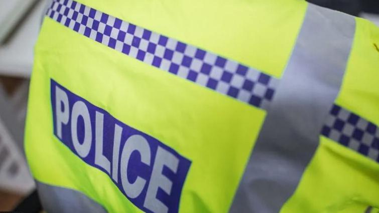 A photo of the back of a high-visibility police vest, with the word "police" on the back. 