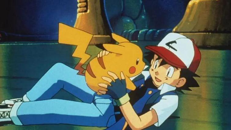 A cartoon boy in a peaked cap holding a little yellow creature with red markings whilst lying down 