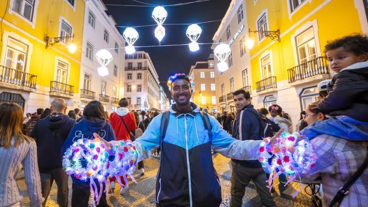 Street vendor smiles on a pretty Lisbon street at night