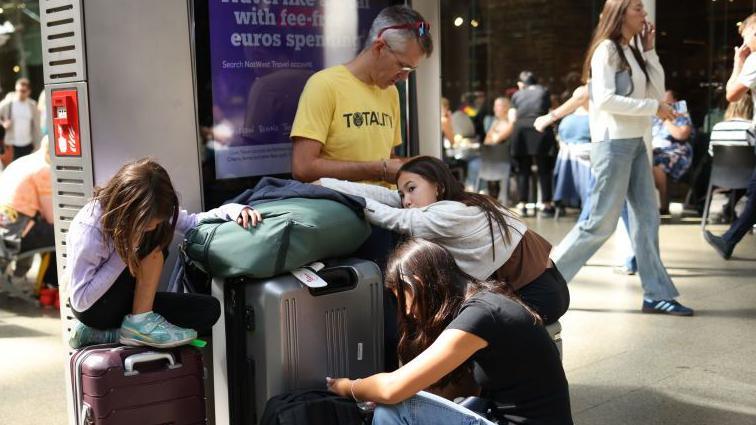 Travelers sit by their bags as the Eurostar service experienced delays at St Pancras International Station.