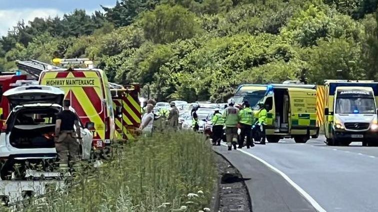 Emergency services vehicles and personnel on the A34 dual carriageway, with stopped cars in the background