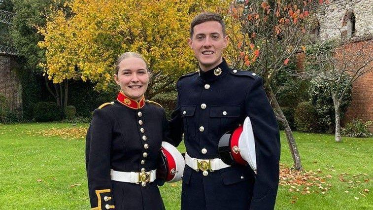 A man and a woman in Royal Marine uniform posing in a garden