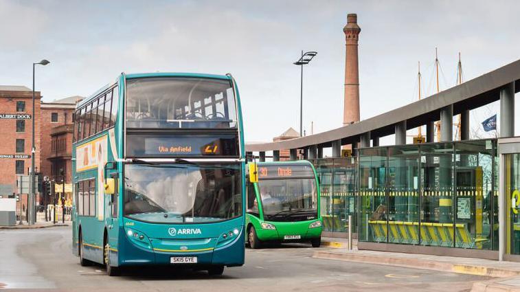 Turquoise and navy double decker bus on road near bus station 