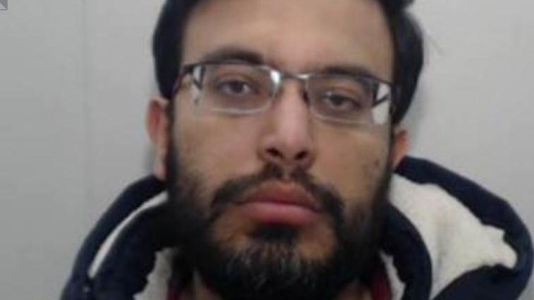 Umair Iqbal has black hair, spectacles with a black beard with grey flecks.