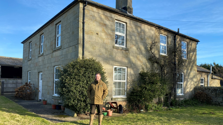 A man outside a big Georgian farmhouse 