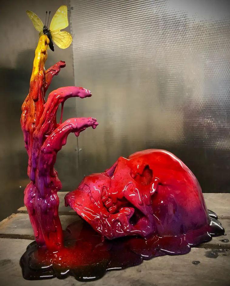 A sculpture of a red resin skull with purple, pink and yellow tones