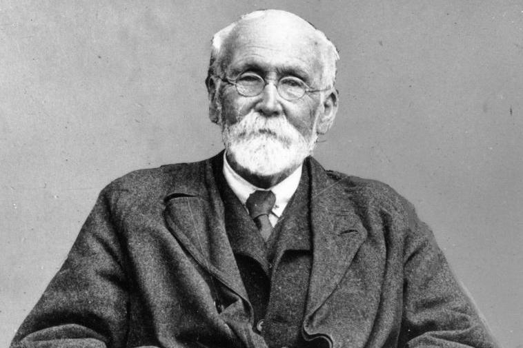 A black and white photo of Joseph Rowntree, who has white facial hair and short white hair. He is wearing rounded glasses.