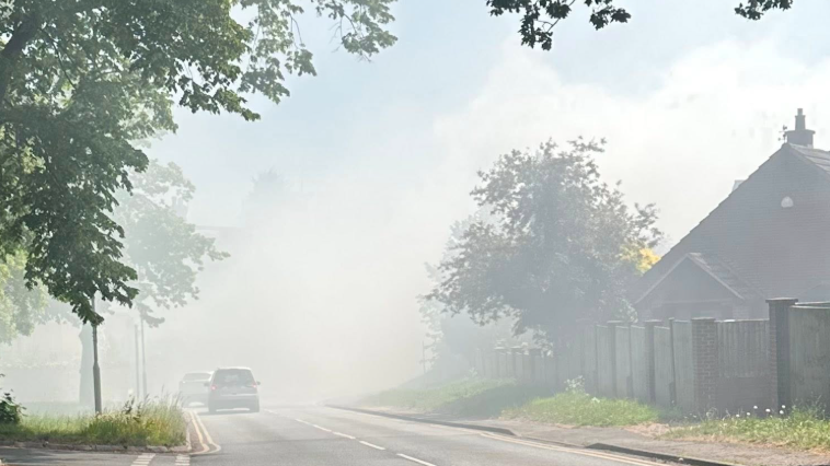 Heavy white smoke billow in a village street