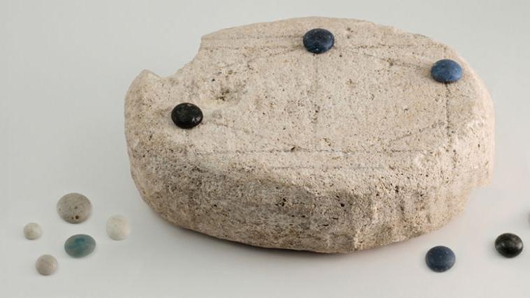 An ancient rock, with smaller coloured stones placed on top of it, and around it.