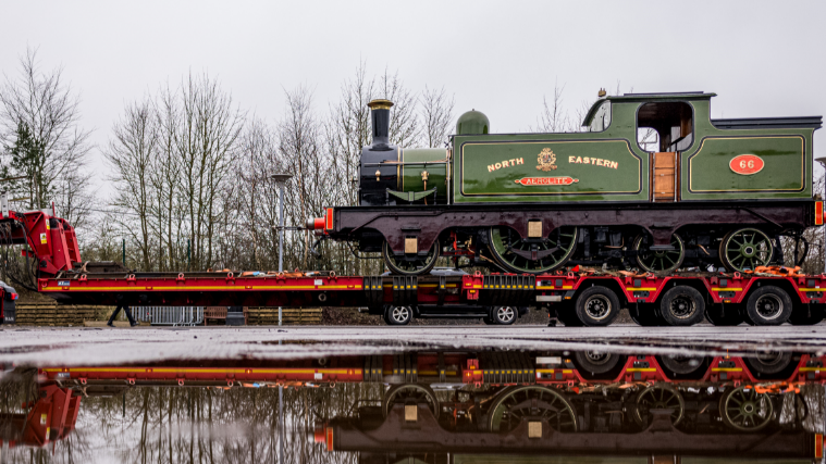 A historic engine being shunted into the display hall on the back of a carrier vehicle