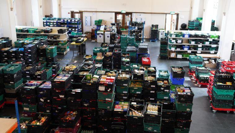 A wide shot of hundreds of food crates stacked up in a large warehouse. 