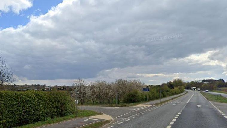 A dual carriageway road with one carriageway empty but four oncoming vehicles seen in the distance.