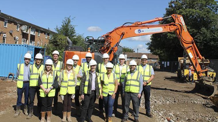 A team of workers in high-vis jackets and hard hats on a building site.