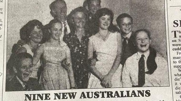 Newspaper cutting showing the MacDonald family after they arrived in Australia. They are laughing and smiling. The headline under the picture reads: 'Nine new Australians'.